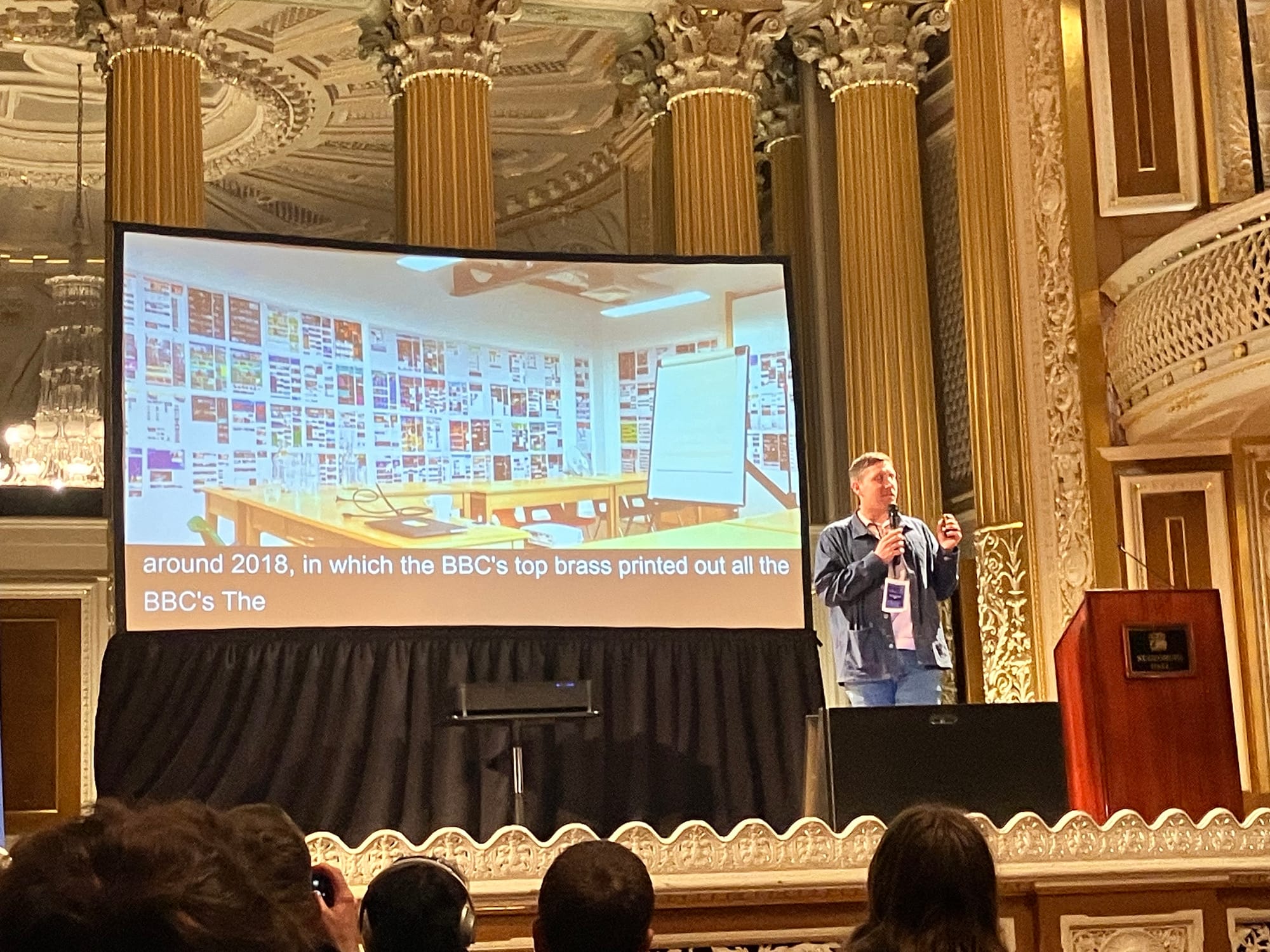 A man talking with an image of a wall covered in different screenshots