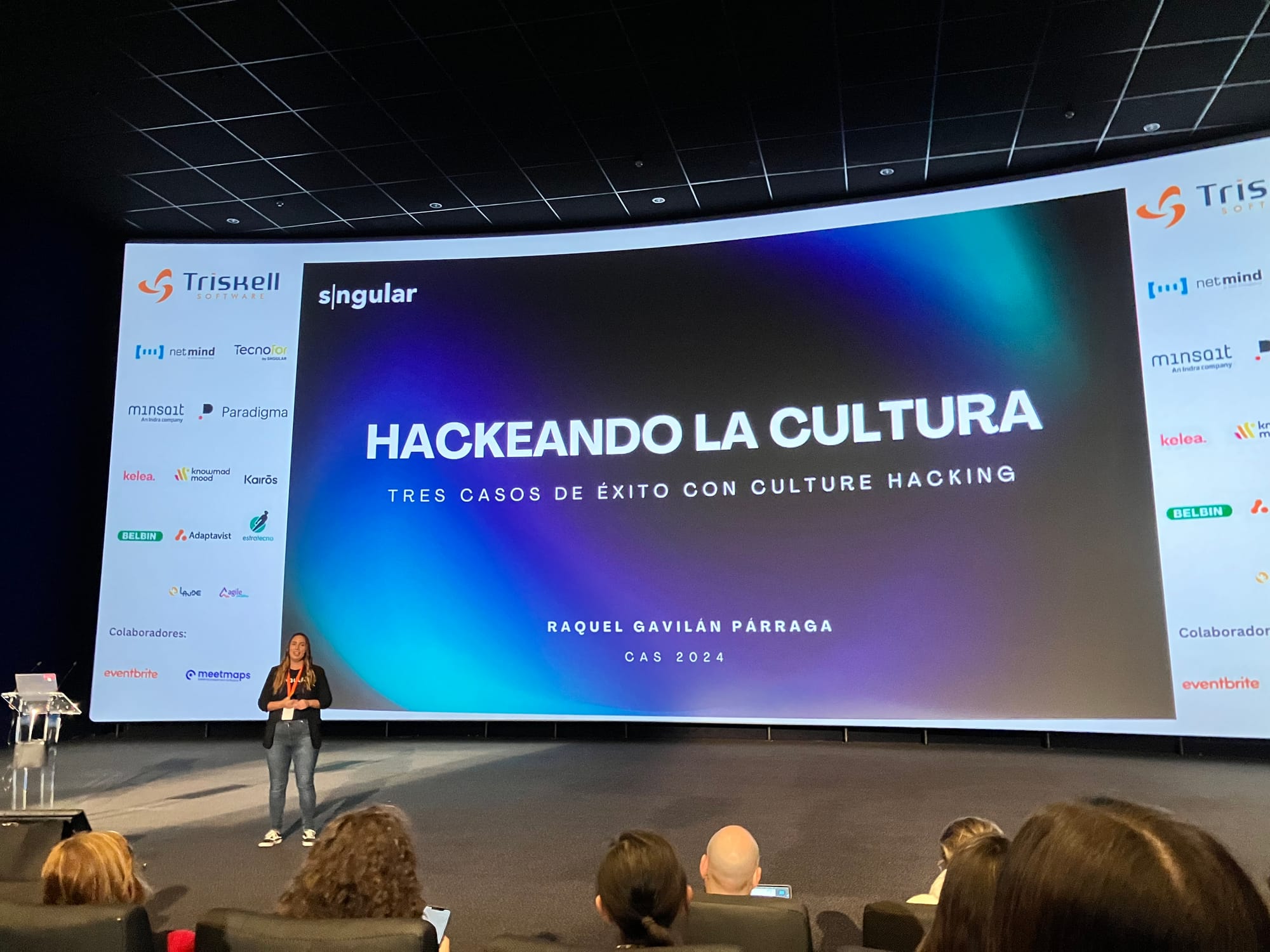 Woman in front of a screen that says 'Hackeando La Cultura'